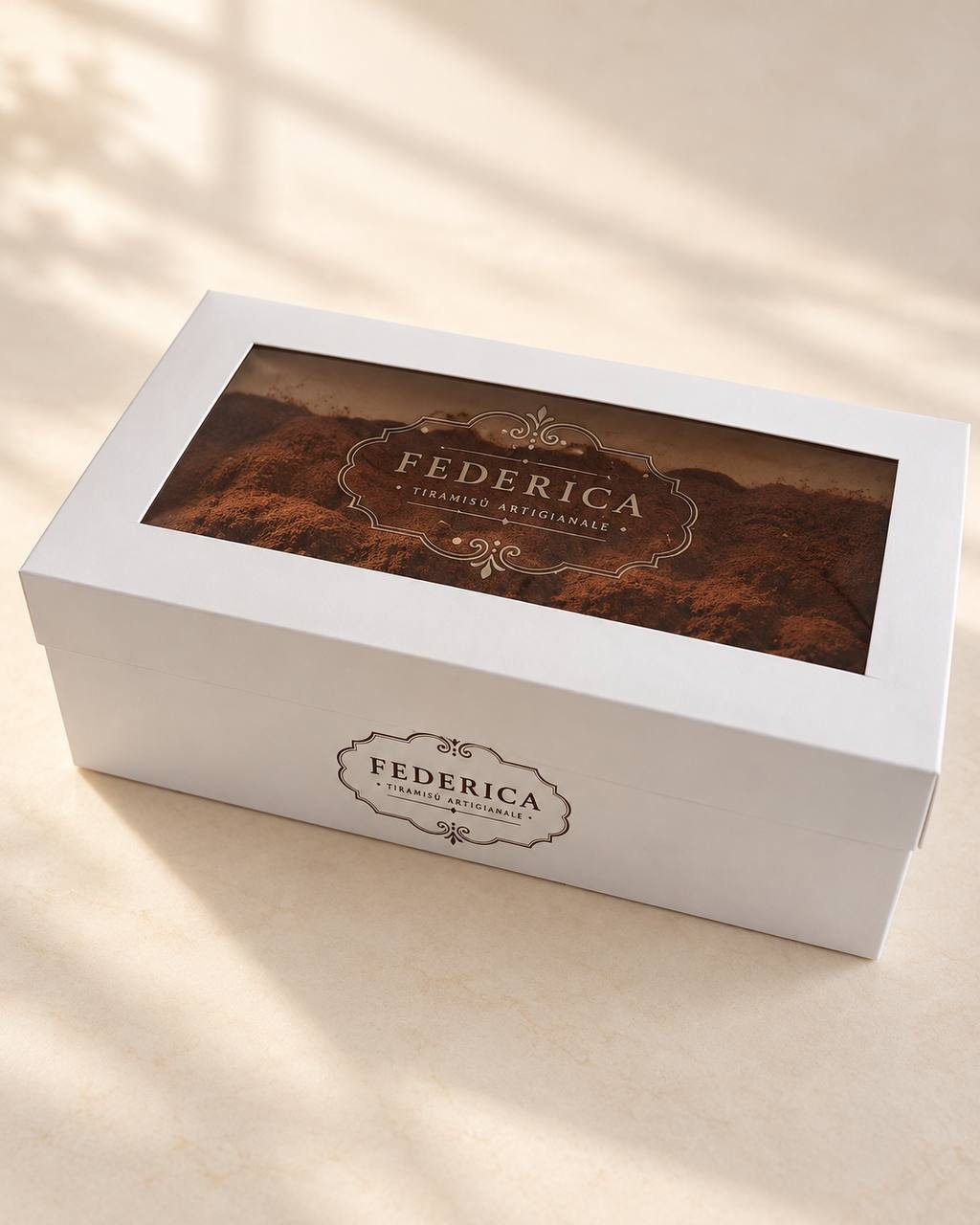 Caja blanca con tapa y ventana de Federica Tiramisù, con el logo en la ventana y en el frente, que deja ver la cocoa del tiramisù.